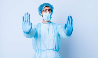 Genç adam ciddi görünüyor, mutsuz, kızgın ve hoşnutsuz giriş ya da her iki avuçta da dur diyor. Coronavirus konsepti