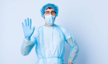 Genç adam gülümsüyor ve arkadaş canlısı görünüyor. Beş ya da beş numarayı gösteriyor. Elleri önde, geriye doğru sayıyor. Coronavirus konsepti
