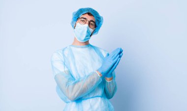 Genç adam mutlu ve başarılı hissediyor, gülümsüyor ve alkışlıyor, alkışlarla tebrik ediyor. Coronavirus konsepti