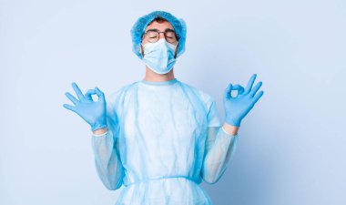 Genç adam odaklanmış ve meditasyon yapıyor, tatmin olmuş ve rahatlamış hissediyor, düşünüyor ya da bir seçim yapıyor. Coronavirus konsepti