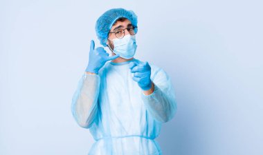 Genç adam neşeyle gülümsüyor ve kamerayı işaret ederek seni daha sonra arıyor, telefonla konuşuyor. Coronavirus konsepti