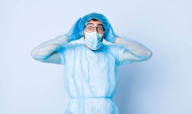 Genç adam heyecanlı ve şaşırmış görünüyor, ağzı açık, elleri başının üstünde, kendini şanslı hissediyor. Coronavirus konsepti