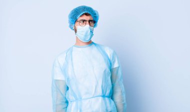 Genç adam üzgün, üzgün ya da kızgın hissediyor ve olumsuz bir tavırla, anlaşmazlık içinde somurtuyor. Coronavirus konsepti
