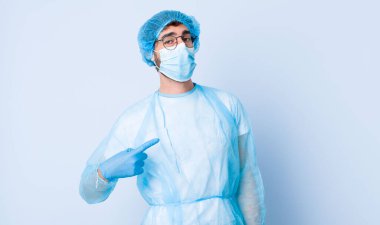 Genç adam gururlu, kendinden emin ve mutlu görünüyor, gülümsüyor ve kendini işaret ediyor ya da bir numara işareti yapıyor. Coronavirus konsepti