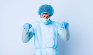 İki eliyle aşağıya doğru bakan ağzı açık genç adam şok olmuş, şaşırmış ve şaşırmış görünüyor. Coronavirus konsepti