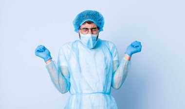 Genç adam son derece mutlu ve şaşırmış görünüyor, başarıyı kutluyor, bağırıyor ve zıplıyor. Coronavirus konsepti