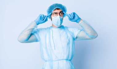 Genç adam odaklanmış ve bir fikir üzerinde kafa yoruyor, bir meydan okumaya ya da soruna bir çözüm hayal ediyor. Coronavirus konsepti