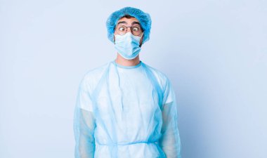 Genç adam şapşal ve komik görünüyor. Şaşı bakışlı, şakacı ve şakacı. Coronavirus konsepti