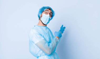 Genç adam mutlu ve şaşırmış hissediyor, şok olmuş bir ifadeyle gülümsüyor ve bir tarafı işaret ediyor. Coronavirus konsepti