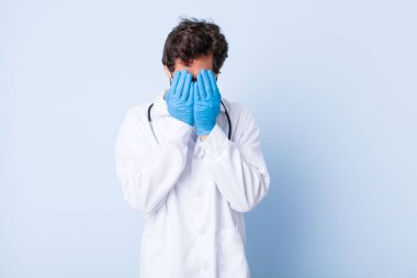 Genç adam üzgün, hayal kırıklığına uğramış, gergin ve depresif, iki eliyle yüzünü kaplayan, ağlayan. Coronavirus konsepti