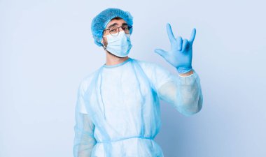 Genç adam kendini mutlu, eğlenceli, kendinden emin, pozitif ve asi hissediyor, elle kaya ya da heavy metal işareti yapıyor. Coronavirus konsepti