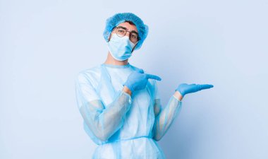 Genç adam neşeyle gülümsüyor ve bir objeyi göstererek veya reklamını yaparak avucundaki kopya alanını işaret ediyor. Coronavirus konsepti