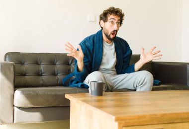 Oturma odasında kanepede oturup televizyon ya da bilgisayar izleyen genç havalı bir adam.