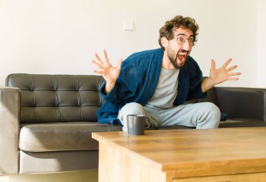 Oturma odasında kanepede oturup televizyon ya da bilgisayar izleyen genç havalı bir adam.