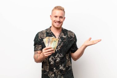 Genç sarışın adam mutlu bir şekilde gülümsüyor, kendini mutlu hissediyor ve fotokopi odasında bir konsept gösteriyor.