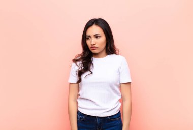 Genç, Latin, güzel bir kadın üzgün, üzgün ya da kızgın. Olumsuz bir tavır sergiliyor, düz duvara karşı anlaşmazlıkla somurtuyor.