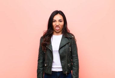 Genç, Latin, güzel bir kadın tiksinmiş ve rahatsız olmuş hissediyor. Dilini dışarı çıkarıyor. Çirkin bir şeyden hoşlanmıyor ve düz duvara karşı iğrenç.