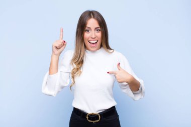 Genç ve güzel İspanyol kadın gururlu ve şaşırmış hissediyor, kendine güvenerek, mavi duvara karşı başarılı olduğunu hissediyor.