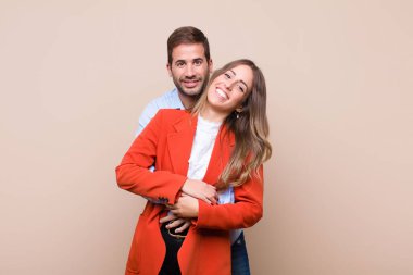 Genç ve güzel bir çift bej düz duvara karşı