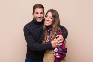 Genç ve güzel bir çift bej düz duvara karşı