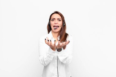 Genç ve güzel bir kadın umutsuz ve hayal kırıklığına uğramış görünüyor, stresli, mutsuz ve sinirli, kulaklık ve mikrofonla bağırıyor ve çığlık atıyor.