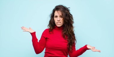 Genç ve güzel bir kadın şaşkın ve kafası karışmış hissediyor. Doğru cevap ya da karardan emin değil. Mavi duvara karşı bir seçim yapmaya çalışıyor.