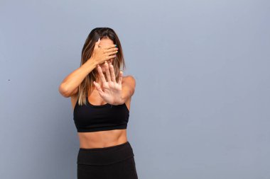 Genç, güzel bir kadın yüzünü eliyle kapatıyor ve kamerayı durdurmak için diğer elini öne koyuyor. Fotoğraf ya da resimleri reddediyor.