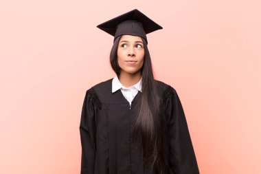 Endişeli, kafası karışık, cahil bir ifadeyle genç Latin kız öğrenci kopya alanı arıyor, şüphe ediyor.