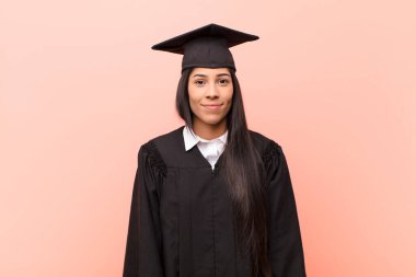 Genç Latin kız öğrenci pozitif ve kendinden emin gülümsüyor. Tatmin olmuş, arkadaş canlısı ve mutlu görünüyor.