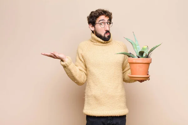 Jonge Koele Man Houdt Een Cactus Plant Tegen Platte Muur — Stockfoto