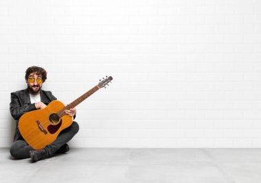 Genç müzisyen kafası karışmış ve kafası karışmış görünüyor. Sinirli bir hareketle dudağını ısırıyor. Gitar, rock 'n roll konseptiyle ilgili sorunun cevabını bilmiyor.