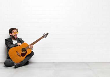 Genç müzisyen, büyük, dost canlısı, kaygısız bir gülümseme, pozitif, rahat ve mutlu görünüyor, gitar, rock 'n roll konseptiyle takılıyor.