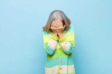 Yaşlı ya da orta yaşlı güzel bir kadın üzgün, hayal kırıklığına uğramış, gergin ve depresif, iki eliyle yüzünü kaplayan, ağlayan