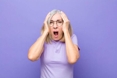 Yaşlı ya da orta yaşlı hoş bir kadın. Şok olmuş, korkmuş ya da endişeli görünüyor. Ağzı sonuna kadar açık ve iki kulağını da elleriyle kapatıyor.