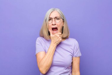 Yaşlı ya da orta yaşlı, ağzı ve gözleri açık, eli çenesinde olan, hoş olmayan bir şok geçiren, ne ya da vay canına diyen güzel bir kadın.