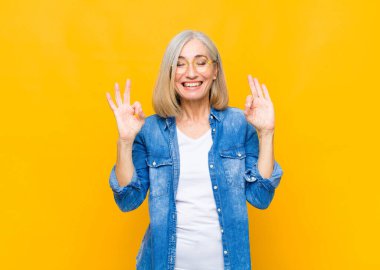 Yaşlı ya da orta yaşlı güzel bir kadın konsantre olmuş ve meditasyon yapıyor, tatmin olmuş ve rahatlamış hissediyor, düşünüyor ya da bir seçim yapıyor.