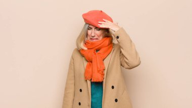 Yaşlı ya da orta yaşlı güzel bir kadın stresli, yorgun ve hayal kırıklığına uğramış görünüyor alnındaki teri kurutuyor, umutsuz ve bitkin hissediyor.