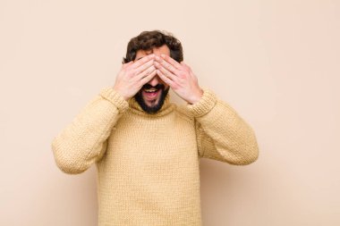 Genç havalı adam gülümsüyor ve mutlu hissediyor, iki eliyle gözlerini kapatıyor ve düz duvara karşı inanılmaz bir sürpriz bekliyor.