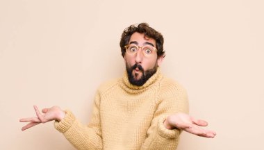 Şaşkın, kafası karışmış ve stresli görünen genç adam farklı seçenekler arasında merak içinde, düz duvara karşı kararsız hissediyor.