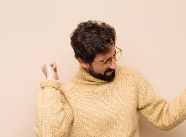 Genç havalı adam gülümsüyor, tasasız ve mutlu hissediyor, dans ediyor ve müzik dinliyor, düz duvara karşı bir partide eğleniyor.