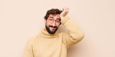 Genç havalı adam mutlu, şaşkın ve şaşırmış görünüyor, gülümsüyor ve düz duvara karşı inanılmaz ve inanılmaz iyi haberler veriyor.