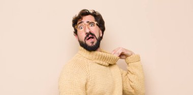 Havalı genç adam stresli, endişeli, yorgun ve hayal kırıklığına uğramış, gömleğini çekmiş, düz duvara karşı sorunlu görünüyor.