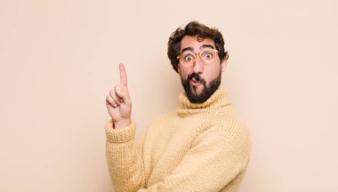 Genç, havalı bir adam gülümsüyor ve arkadaş canlısı görünüyor. Bir numara ya da ilk eli önde, düz duvara doğru sayıyor.