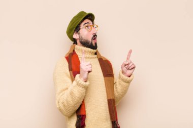 Havalı sakallı genç adam şaşırmış, şaşırmış ve ağzı açık bir şekilde uzayı kopyalamak için iki elini havaya kaldırıyor.