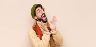 Genç havalı sakallı adam profili, mutlu ve heyecanlı görünüyor, bağırıyor ve kenardaki boşluğu kopyalamak için arıyor.