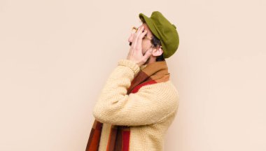 Genç havalı sakallı adam uykulu görünüyor, sıkılmış ve esniyor, baş ağrısı ve yüzünün yarısını kaplayan bir eliyle