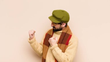 Genç havalı sakallı adam kendinden emin, sinirli, güçlü ve agresif görünüyor. Yumrukları boks pozisyonunda dövüşmeye hazır.