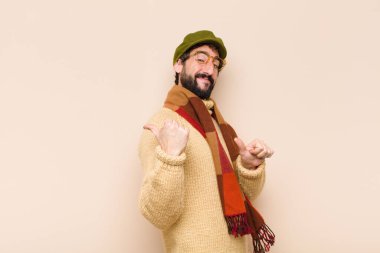 Genç, havalı sakallı, neşeli ve tesadüfen gülümseyen bir adam yan taraftaki fotokopi alanını gösteriyor, mutlu ve tatmin olmuş hissediyor.