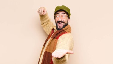 Genç, sakallı, neşeli bir şekilde gülümseyen ve bir objeyi gösteren ya da reklamını yapan, avucundaki fotokopi alanını gösteren bir adam.