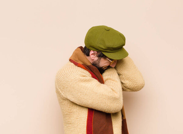 молодой прохладный бородатый мужчина чувствует себя в любви и выглядит мило, очаровательно и счастливо, улыбаясь романтически с руками рядом с лицом
